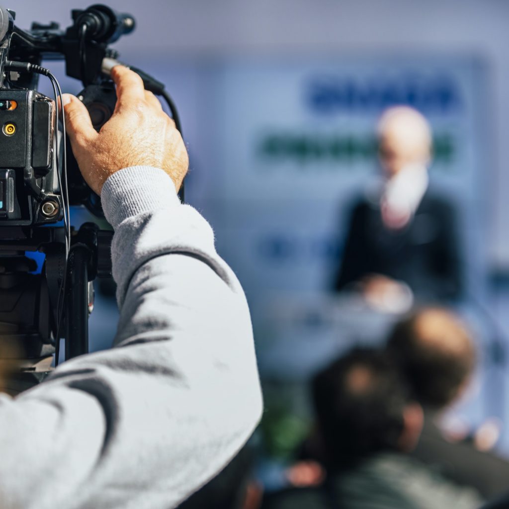 Media Event. Cameraman Recording Speaker On Stage